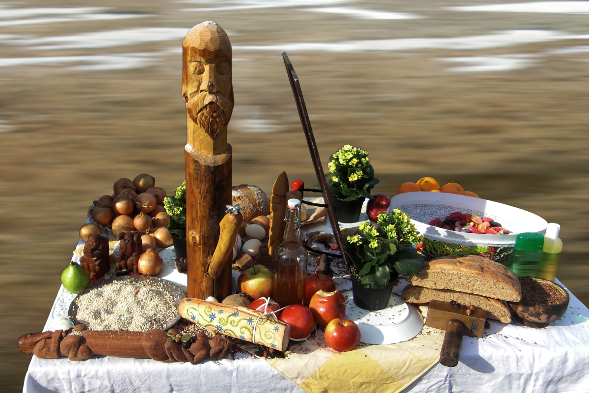 This photo shows a modern Norse pagan altar made for a 2010 spring ceremony in Gamla Uppsala, featuring food, drink, flowers, and carvings of Freyr, Thor, and Odin.