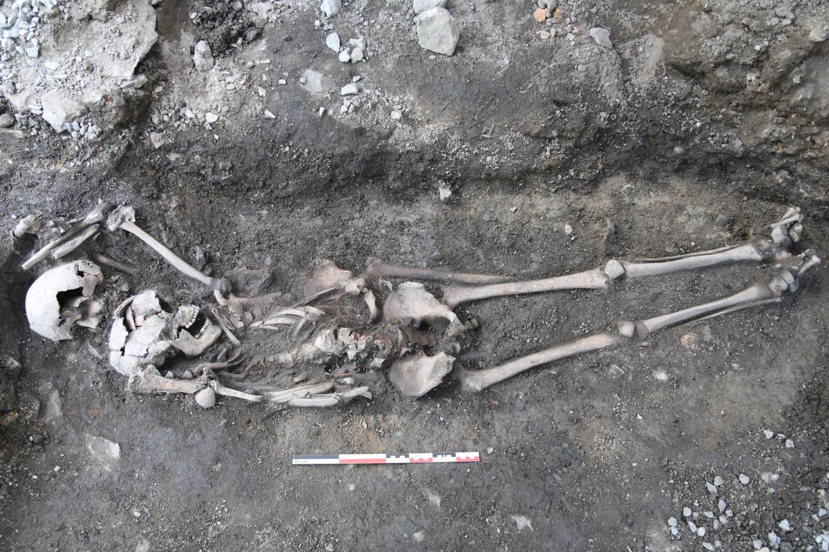 The photo shows the individual lying on top with the skull of skeleton 2 lying under. It's apparent that the top skeleton's arm is raised above his head.
