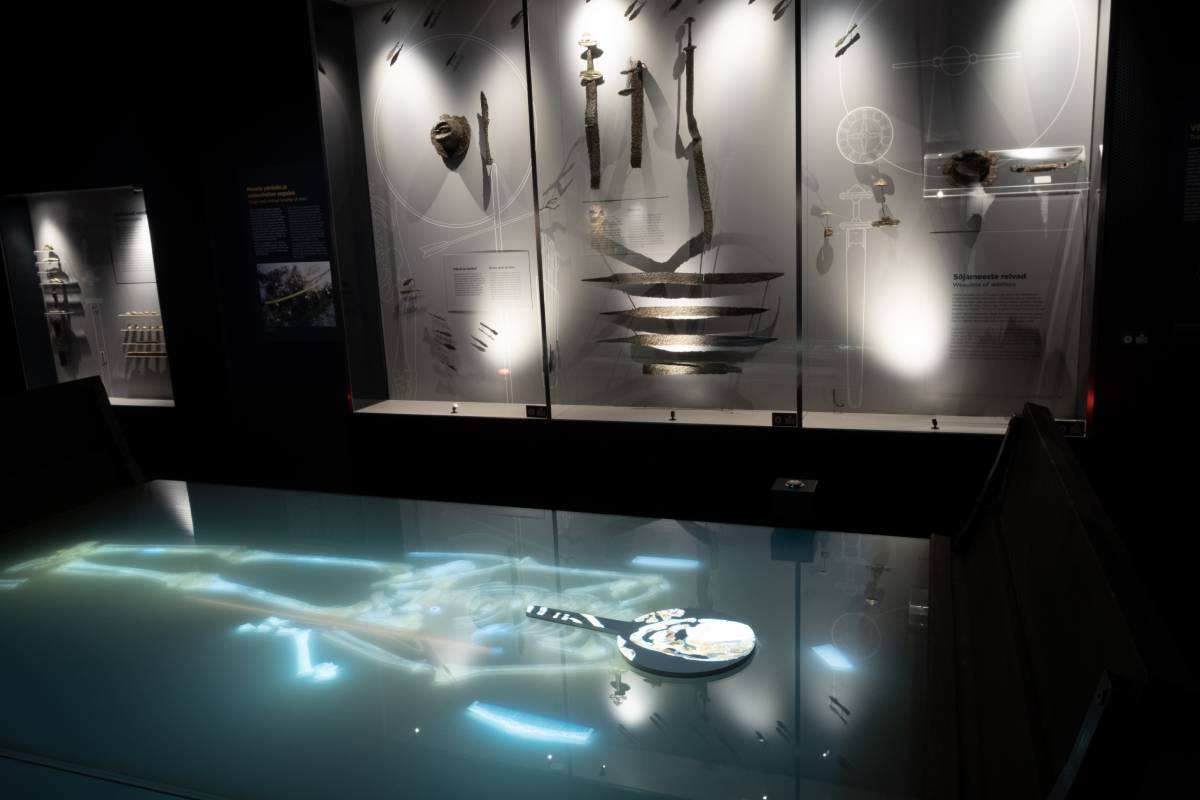 The exhibition at the Vrak Museum presents artifacts from the Salme ship burials, including military equipment, ship fragments, and skeletal remains of over 40 Scandinavian warriors.